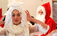 Frau als Christkind verkleidet, ein Weihnachtsmann im Hintergrund