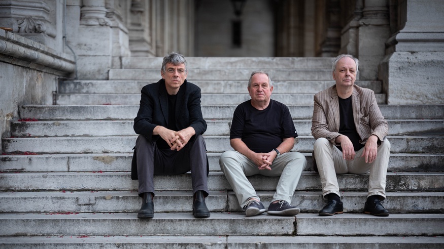 Die Musiker Thomas Lehn, Oskar Aichinger und Georg Graewe sitzend auf einer Stufe.