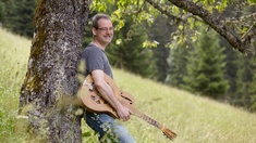 Gottfried Gfrerer © EDWIN STRANNER Der Musiker Gottfried Gfrerer lehnt mit seiner Resonatorgitarre an einem Baum.