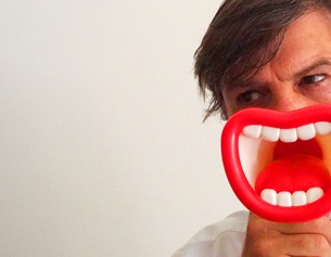(c) netzzeit Mann vor weißem Hintergrund mit Plastiklippen vorm Gesicht