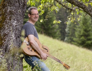 Gottfried Gfrerer © EDWIN STRANNER Der Musiker Gottfried Gfrerer lehnt mit seiner Resonatorgitarre an einem Baum.