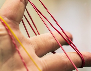 Symbolbild Gummiringerl-Fadenspiel für die Wissenschaftsreihe Was die Welt zusammenhält